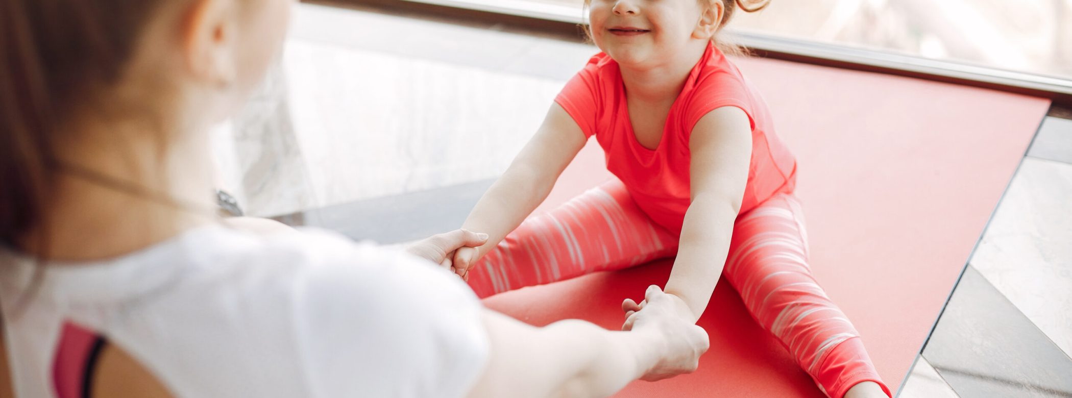 Woman in a sportswear. Mother with little daughter. Family are engaged in gymnastics in a gym